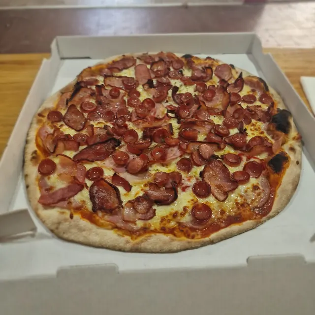 Pizza de un cliente recién salida del horno de leña