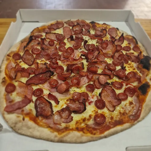 Pizza de un cliente recién salida del horno de leña