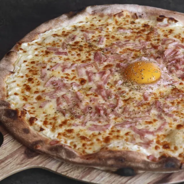 Pizza de un cliente recién salida del horno de leña
