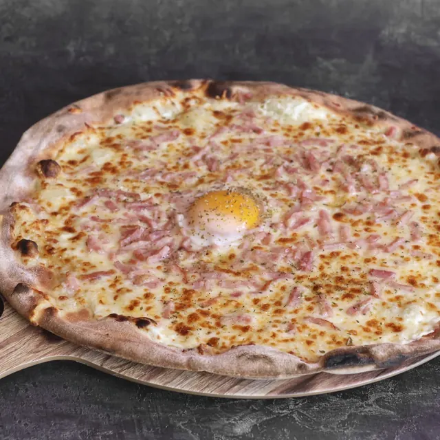 Pizza de un cliente recién salida del horno de leña