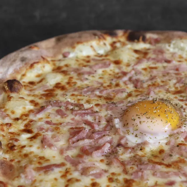 Pizza de un cliente recién salida del horno de leña
