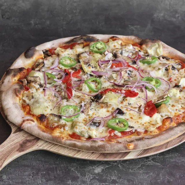 Pizza de un cliente recién salida del horno de leña