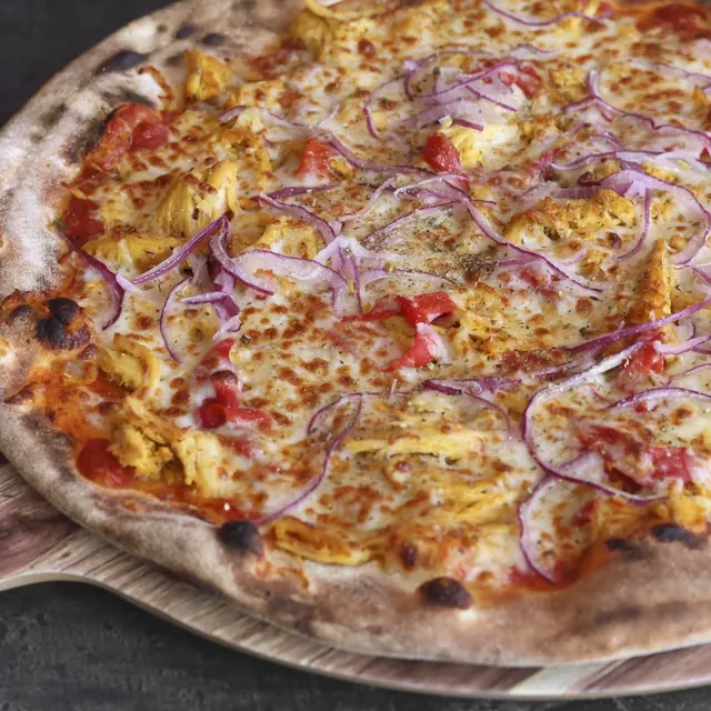 Pizza de un cliente recién salida del horno de leña