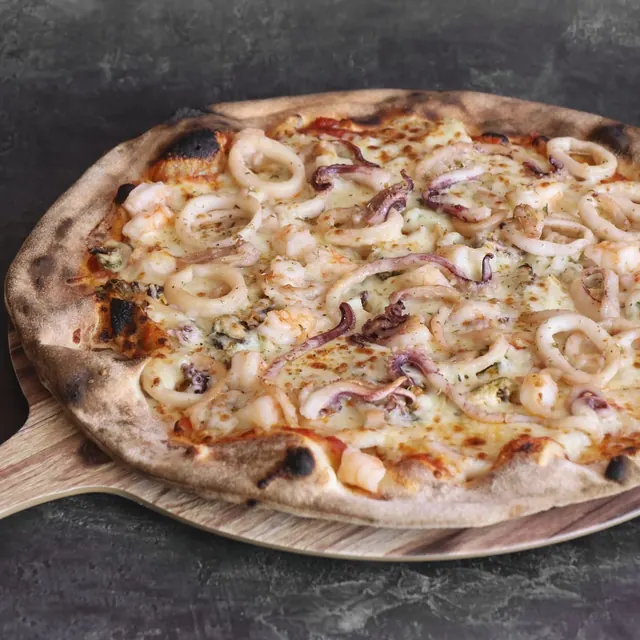Pizza de un cliente recién salida del horno de leña