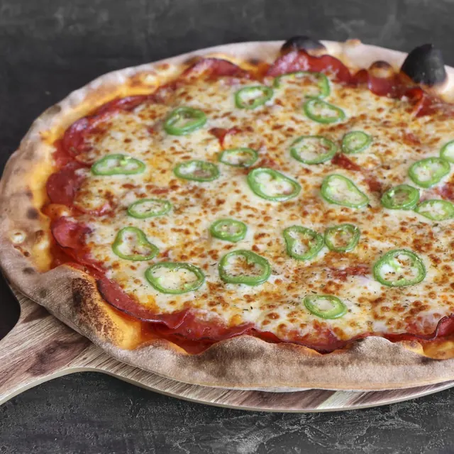Pizza de un cliente recién salida del horno de leña
