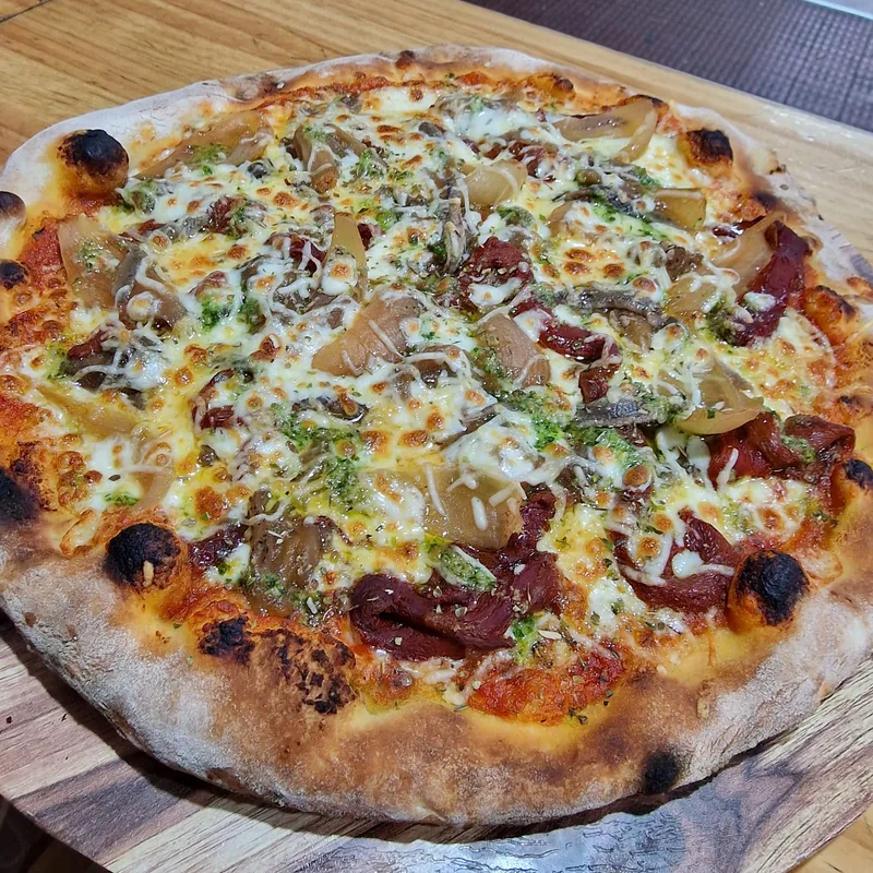 Pizza con bordes tostados por la leña sobre tabla de madera