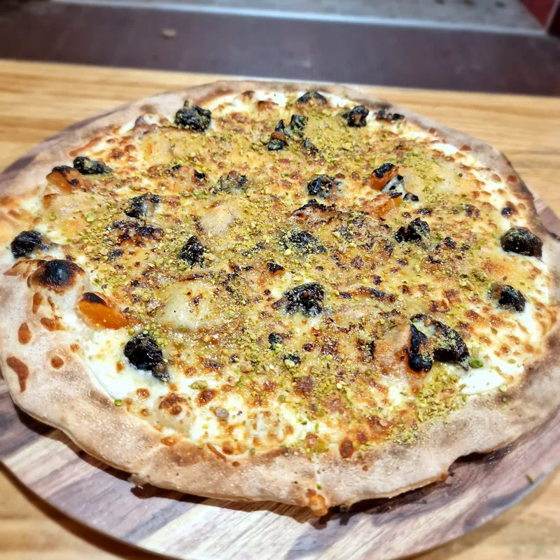 Pizza dulce con pistacho sobre tabla de madera